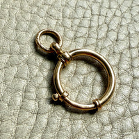18k Gold antique bolt ring jewelry clasp piece on a textured light gray background