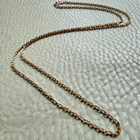 18k Gold chain necklace on a textured light green surface penelopepenelope.com