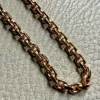 Gold chain on a light gray textured surface. Penelope Penelope vintage gold jewelry