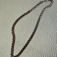 Silver chain necklace on a textured beige surface