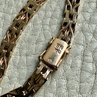 Gold chain bracelet with clasp on a textured light blue background