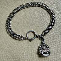 antique Silver watch chain with large bolt clasp on a textured beige surface