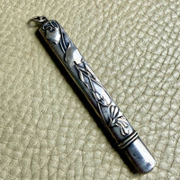 Silver art nouveau pencil case with intricate designs on a textured beige surface