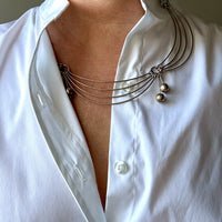 Person wearing a white shirt with a silver collar necklace