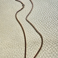 Gold chain necklace on a textured beige surface