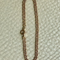 Gold chain bracelet on a textured light green background