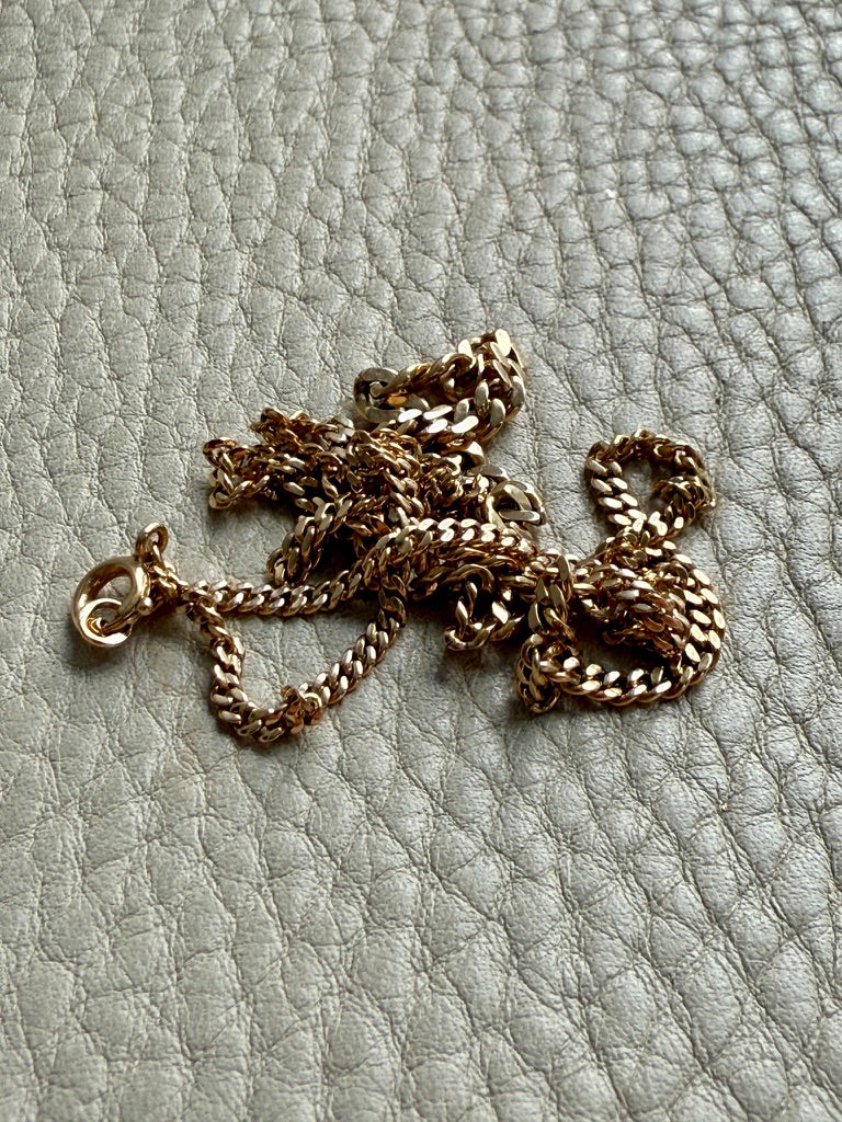 Gold chain necklace on a textured light gray surface