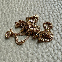 Gold chain necklace on a textured light gray surface