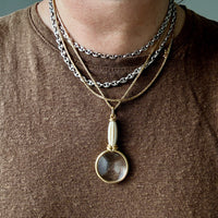 Necklace with a pendant worn by a person on a brown shirt