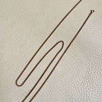 Gold chain on a textured beige surface