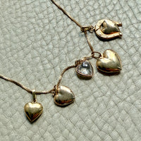 Gold heart-shaped necklace on a textured light gray background