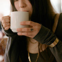 Woman drinking from a white mug with a blurred background