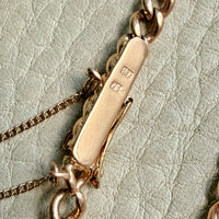 Close-up of a gold chain with a clasp on a light gray textured background