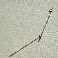 18k gold antique brooch on a textured beige background