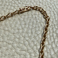 14k gold oval link Gold chain necklace on a textured light gray surface