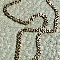 Gold chain necklace on a textured light gray surface