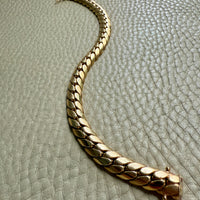 Gold bracelet on a textured light gray surface. Penelope Penelope Vintage 18k gold fine jewelry