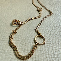 Gold watch chain necklace on a textured light gray surface. PenelopePenelope.com