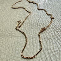 Gold chain necklace on a textured light gray surface