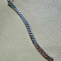 silver bracelet with textured design on a textured surface