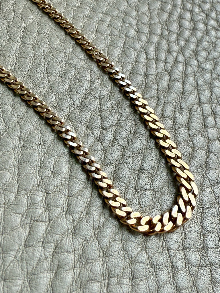 Gold chain necklace on a textured gray surface