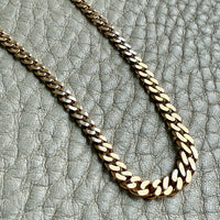 Gold chain necklace on a textured gray surface