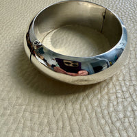 Silver bangle on a textured beige surface