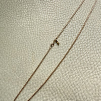 Gold chain necklace on a textured beige surface