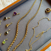 Gold necklaces and earrings on a gray surface with a wooden border.