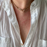 Close-up of a person wearing a white shirt and gold watch chain necklace.