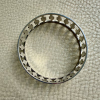 silver vintage bangle with decorative cutout on a textured beige surface