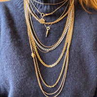 Gold necklaces on a person wearing a blue sweater
