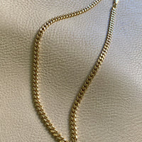 18k gold curb chain on gray textured surface