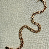 18k Gold chain bracelet on a textured light green surface