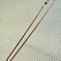 Gold chain necklace on a textured light gray background