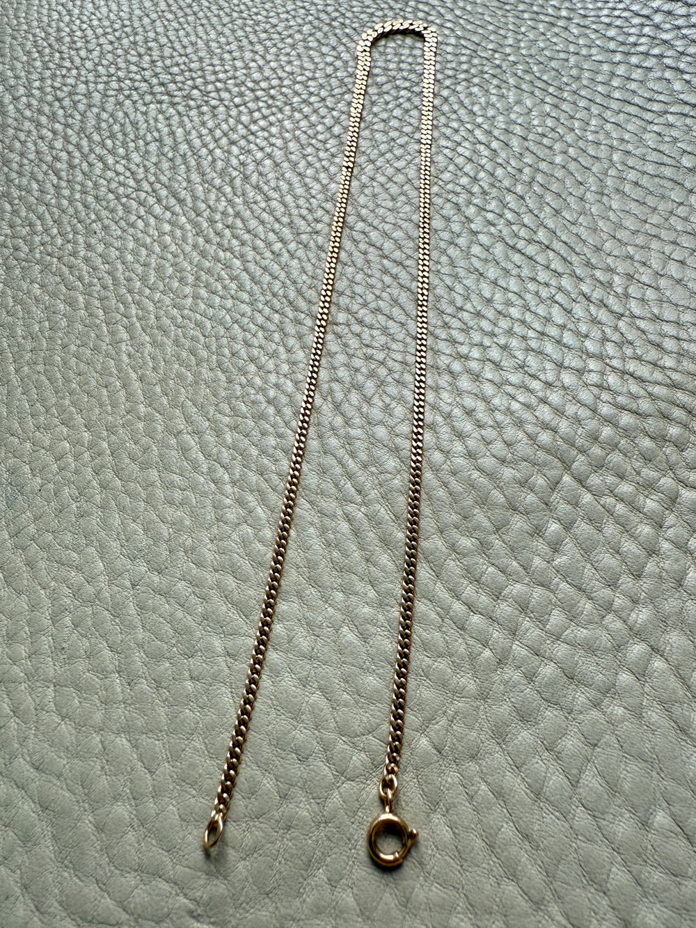 Gold chain necklace on a textured gray surface