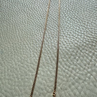 Gold chain necklace on a textured gray surface