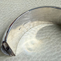 Close-up of a silver bracelet on a textured beige surface