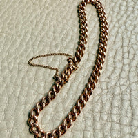 Gold curb chain bracelet on a textured beige surface