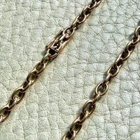 14k gold oval link Gold chain necklace on a textured light gray surface