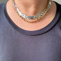 Two necklaces, one gold and one silver, draped on a neck