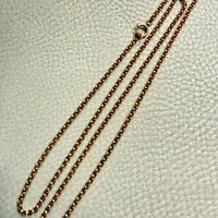 18k Gold antique rolo link necklace on a textured light gray surface