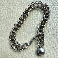 Silver chain bracelet with a pendant on a textured light gray background