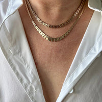 Close-up of a person wearing a white shirt with gold necklaces.