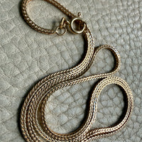Vintage Italian 18k Gold wheat link necklace on a textured gray surface PenelopePenelope.com