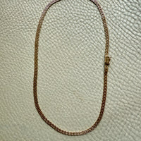 Gold chain necklace on a textured beige surface