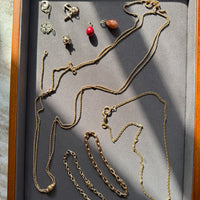 Jewelry set including necklaces and pendants displayed in a wooden box with a gray interior.