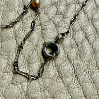 detail of french antique platinum Necklace with pearl beads on a textured beige surface