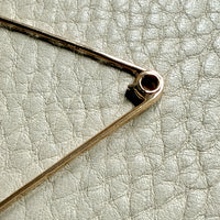 Close-up of a gold brooch on a light gray textured background