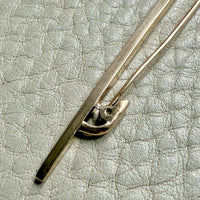 Close-up of a 18k gold antique brooch on a textured beige background